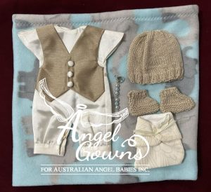 An example of an urgent package containing a blanket, knitted or crocheted beanie, crocheted booties, a nappy, a keepsake charm, and an angel gown. This set is for a boy and is bronze and blue with a vest and the gown is styled like a romper.