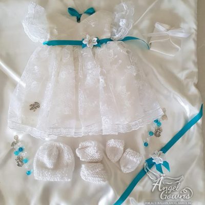 Alt text: A package for a girl displaying a lacy gown; blanket; matching beanie, mittens, booties; nappy and a keepsake charm